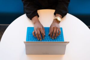 Persona escribiendo en el teclado de un portátil sobre una mesa de madera